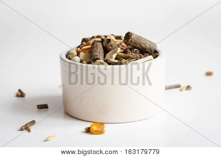 dry food for rodents in bowl on white background close up