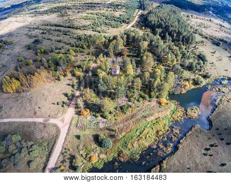 Aerial view of an abandoned church and cemetery near the river Volchina. Shooting from height of the bird's flight. Maksatikhinsky District Tver Region.