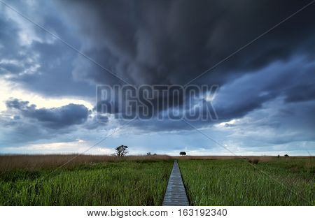 dramatic stormy clouds over pier path on coast