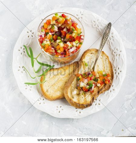 Salad Salsa of colorful vegetables in a glass batch with toasted grilled on a light background. Top view