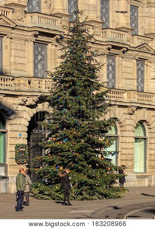 Zurich, Switzerland - 27 December, 2016: people and Christmas tree on Paradeplatz square, Credit Suisse bank office building in the background. Zurich is the largest city in Switzerland and the capital of the Swiss Canton of Zurich.