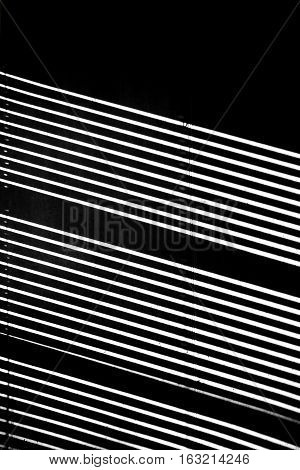A half-open jalousie throws at the dark walls of a niche light stripes.