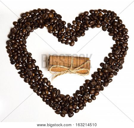 Coffee beans in heart shape and cinnamon in the center on a white background