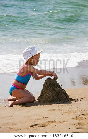 Little girl playing with sand on the beach