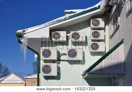 Several air conditioners on the wall of an office building.