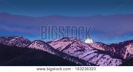Moon rise over mountains with alpen glow pink light