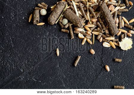 dry food for rodents on dark background top view.