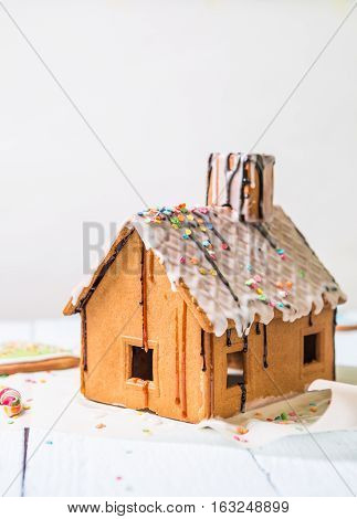 Homemade gingerbread house with glaze and confectionery sprinkling on white background