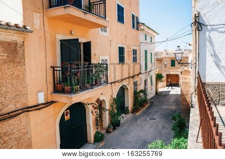 Alcudia Mallorca Spain - May 23 2015: Adult walks through the narrow streets of historical town part of Alcudia with its traditional house and architecture