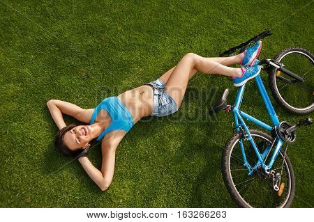 the woman lies on the grass and enjoy the summer sun after a bike ride