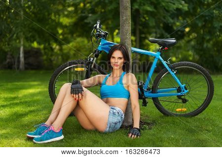 woman sitting on the grass who your bike