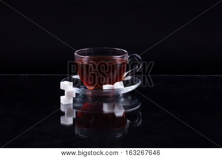 Cup Of Black Tea With Slices Of Sugar On A Black Background