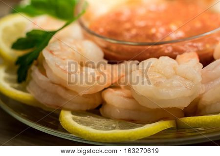 Shrimp cocktail over lemon rounds served with cocktail sauce with parsley sprigs