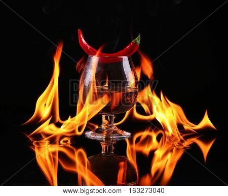 Hot Chili Pepper In A  Cognac Ballon With A Fire On A Black Background