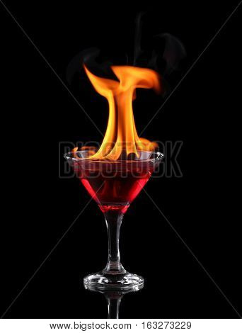 Flaming cocktail in glass over black background