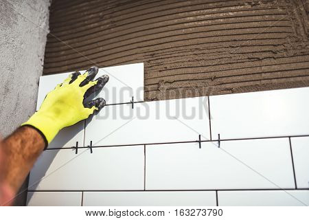 Industrial Worker Holding Ceramic Tiles And Applying Cement Adhesive On Bathroom Walls