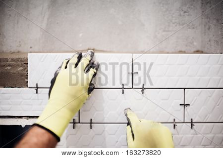 Professional Industrial Worker Installing Small Ceramic Tiles In Bathroom During Renovation Works