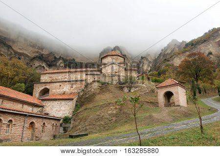 Great brick walls of historical Orthodox monastery Shio-Mgvime Christian built in foggy canyon in 6th century in Mtskheta, Georgia.