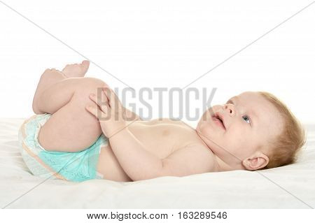 dorable baby boy in pampers on blanket on a white background