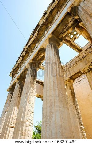 Looking up view of famous Greek temple pillars against clear blue sky in Greece
