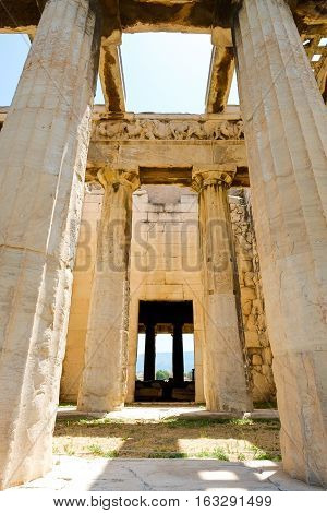Looking up view of famous Greek temple pillars against clear blue sky in Greece