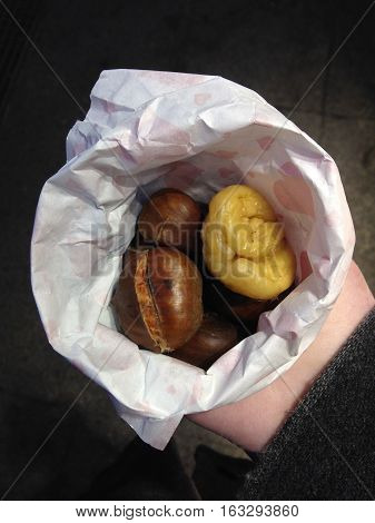 male hand holding cornet with roasted chestnuts, street food known as maroni in Germany