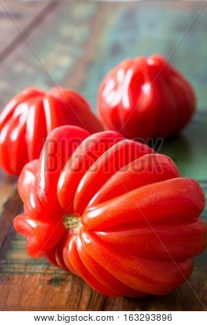 Three oxheart tomatoes on a colorful table in vintage style