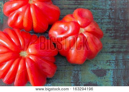 Top view of three oxheart tomatoes on a wooden table in vintage style