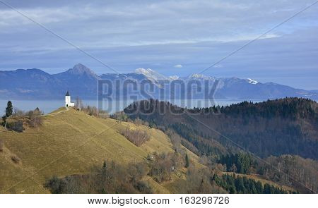 The Church of Saints Primus and Felician near Jamnik in north west Slovenia with the Julian Alps in the background.