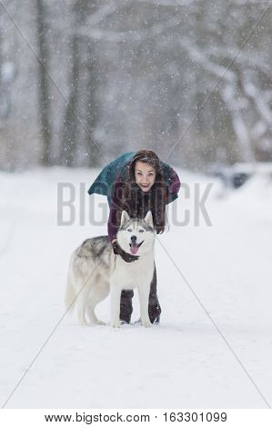 Caucasian Brunette Girl Posing With Her Husky Dog Outside in Winter Forest. Vertical Image Composition