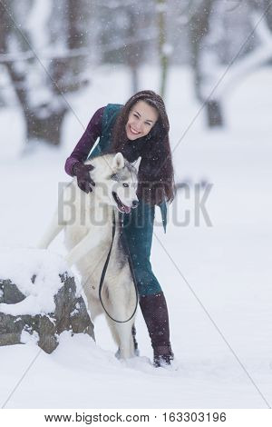 Home Pets Concept and Ideas. Happy Caucasian Brunette Woman and Her Husky Dog. Playing Outdoors in Winter Forest. Vertical Orientation