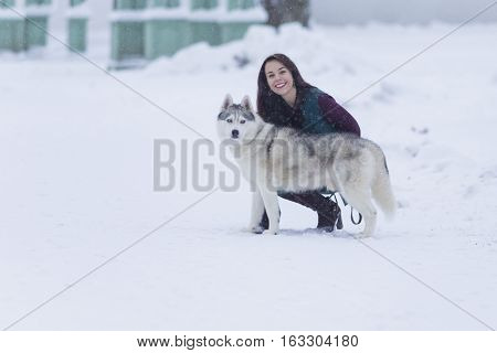 Portrait of Pretty Smiling Woman Hugging Her Husky Dog Outside. Horizontal Image Orientation