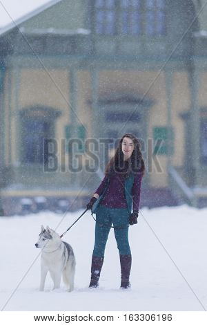 Caucasian Brunette Woman Keeping Her Husky Dog on a Short Leash During a Stroll in Winter Time Outside.Vertical Image Composition