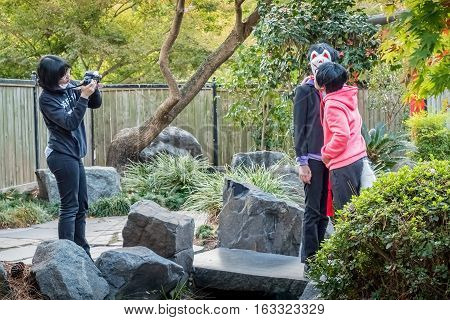 Sydney, Australia - May 22, 2016: At the popular Auburn Botanic Gardens, Japanese Zen Gardens section. Teenagers filming a scene from the popular Japanese fox legend story.