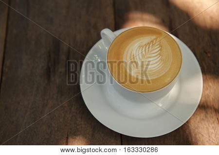 Cup of hot Cappuccino art coffee on wooden table
