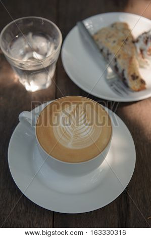 Cup of hot Cappuccino art coffee on wooden table