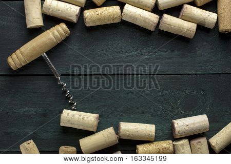 Many wine corks and a vintage cork screw on a dark wooden background texture with copyspace. A horizontal design template for a tasting invitation or restaurant menu