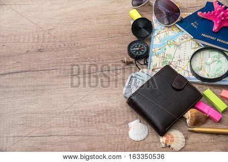 Travel concept - wallet dollar passports compass seashell on wood background