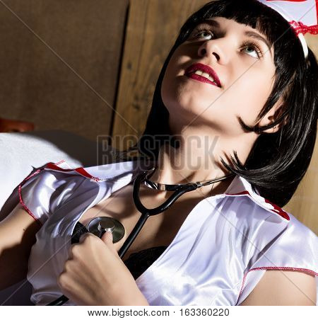 female nurse sexy woman in carnival costume sitting on white sofa holding stethoscope.
