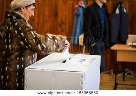 Bucharest Romania - December 11 2016: A woman casts her ballot during voting for parliamentary elections at a polling station in Bucharest Romania.