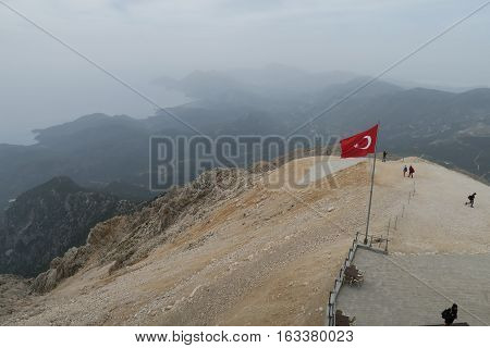Turkish Flag at the Top of the Tahtai Dagi - Olympos Mountain in Kemer with Olympos Beach in the Background and the Mediteranian Sea