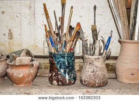 windowsill on which stand in vases tools in pottery. tools for modeling in clay closeup. Creative studio potter. Workplace wizard Crock