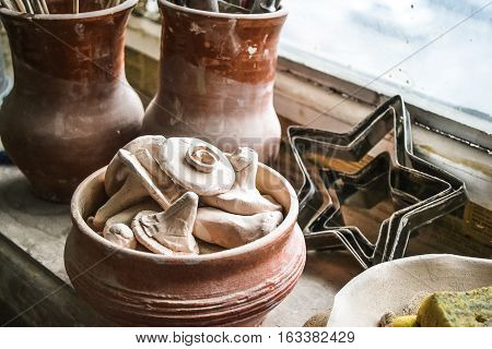 windowsill. many small pottery lying on the plate closeup. Creative studio potter. Workplace wizard Crock pottery
