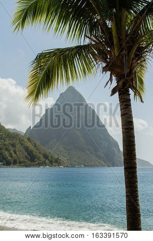 Beach view across the bay at Soufriere to the sea and Piton mountain. Framed with a palm tree