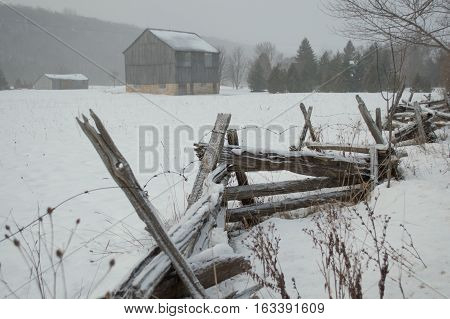 An ontario bank barn with split cedar rail fence in the snow in winter