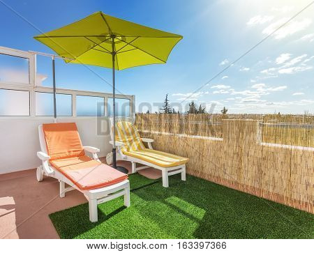 Umbrella and sunbed on the terrace for sunbathing and relaxing. Summer.