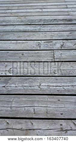 Silvery worn wood planks run horizonally as a background with character. Top planks recede into distance.