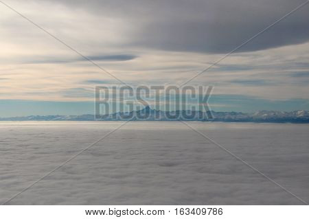 Airview of the sky with clouds and Mont Blanc at horizon.