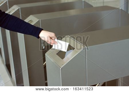Woman's hand puts white plastic card to reader access security control system closeup