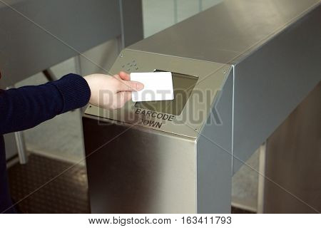 Woman's hand puts white plastic card to reader security access control system closeup